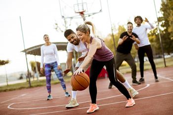 A group of young adults playing basketball at a basketball court.at Fountains of Fair Oaks, California